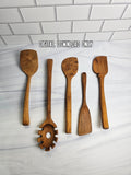 Set of wooden kitchen utensils on a white marble surface with a subway tile background.